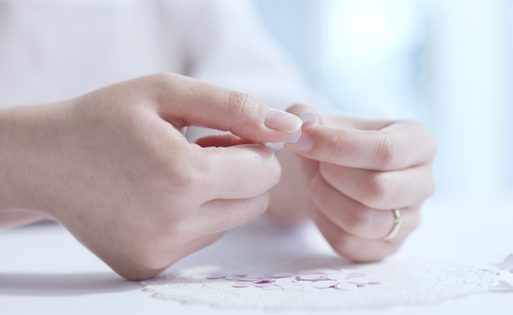 The delicate hand-crafting process of a paper artist shaping cardstock petals.