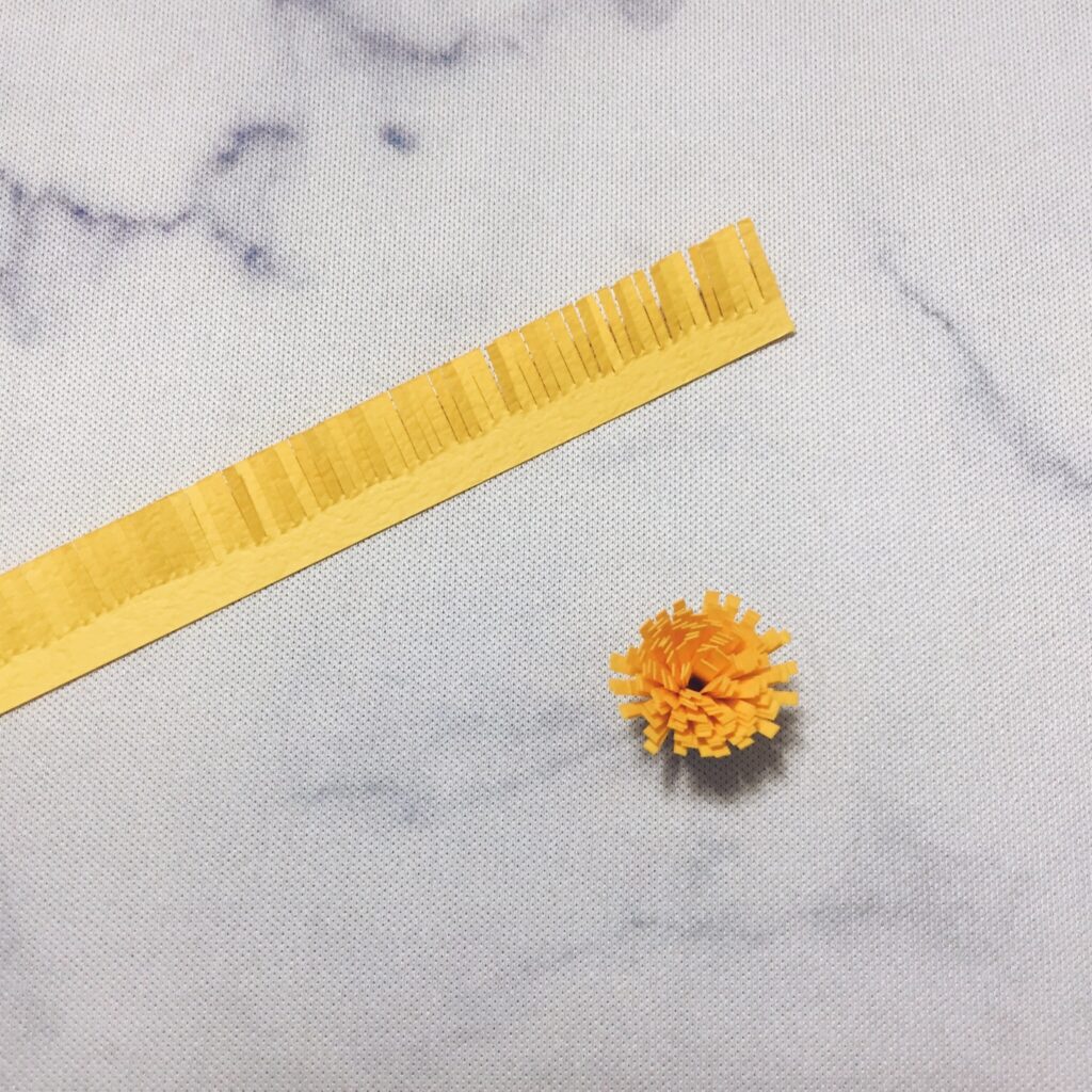 Small yellow paper flower center made from a rolled fringed strip